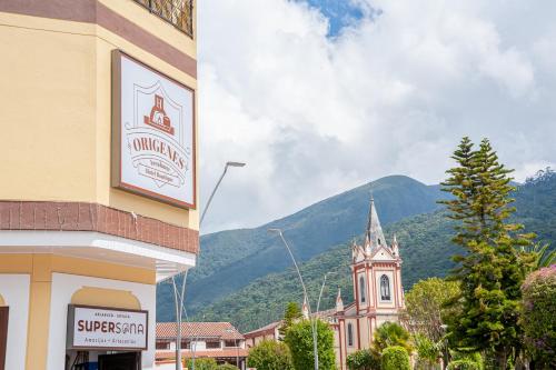 a building with a clock tower next to a mountain at Orígenes Arcabuco Hotel Boutique in Arcabuco