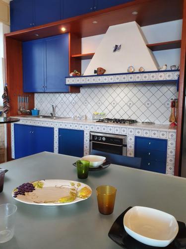 マルツァメミにあるRosa dei Venti Beach Houseのキッチン(青いキャビネット、食器一皿付きのテーブル付)