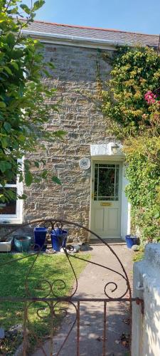 uma casa de pedra com uma mangueira na frente de uma porta em 5 Goonbell em St. Agnes