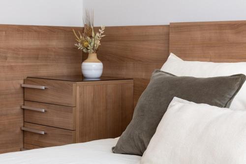 a bed with a wooden head board with a vase on a night stand at AH El Rincón del Condado VUT2805AS in Noreña