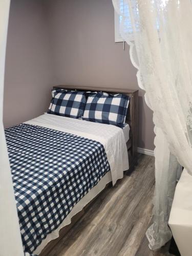 Schlafzimmer mit einem Bett mit einer blauen und weißen Bettdecke in der Unterkunft Adorable Studio Basement Suite in South Barrie in Barrie