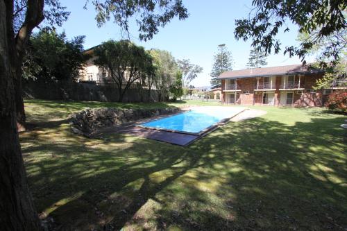 un patio con piscina frente a una casa en Waterview Gosford Motor Inn, en Gosford