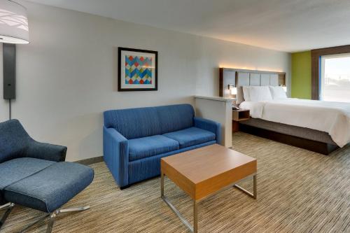 a hotel room with a bed and a blue couch at Holiday Inn Express Lake Worth NW Loop 820 by IHG in Fort Worth
