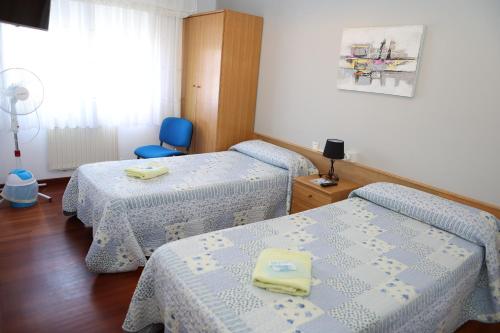 a room with two beds and a blue chair at Albergue Camiño Real in Sigüeiro