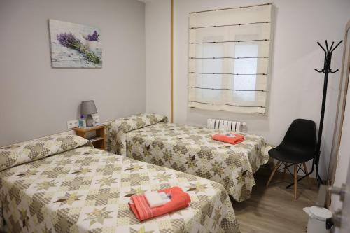 a room with two beds and a chair at Albergue Camiño Real in Sigüeiro