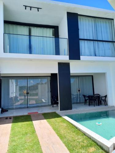 a house with a swimming pool in front of it at VIA CARNEIROS DUPLEX in Praia dos Carneiros