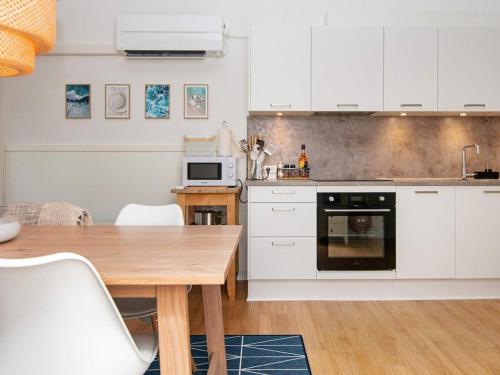 a kitchen with white cabinets and a wooden table at 6 person holiday home in Ringkøbing-By Traum in Ringkøbing