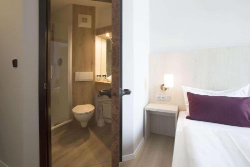 a bedroom with a bed and a bathroom with a toilet at Nautic Hotel Bremerhaven in Bremerhaven