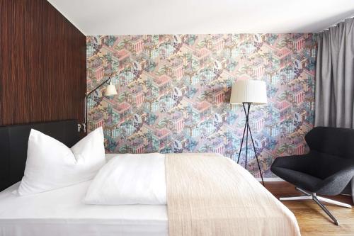 a bedroom with a bed and a chair and a wallpaper at Parkhotel Heilbronn in Heilbronn