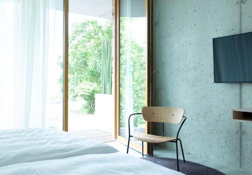 a bedroom with a bed and a chair next to a window at Flowers Hotel Essen in Essen