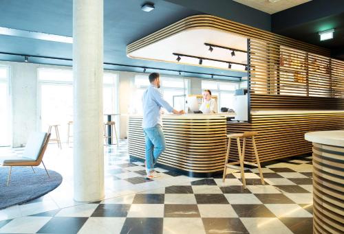a man standing at a counter in a restaurant at Flowers Hotel Essen in Essen