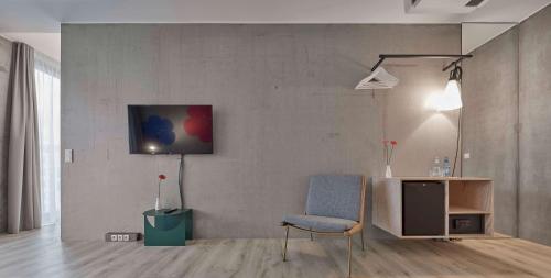 a living room with a chair and a tv on a wall at Flowers Hotel Essen in Essen
