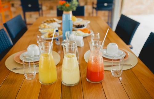 a long wooden table with several glasses of juice at Tapiri Pousada - Rota Ecológica dos Milagres in São Miguel dos Milagres