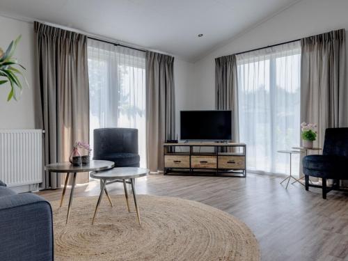 a living room with a flat screen tv and a couch at Chalet by Pond in Eindhoven Holiday Park in Veldhoven