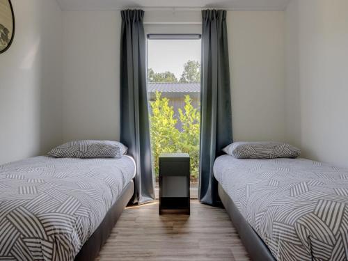 two twin beds in a room with a window at Beautiful chalet with a bath, in a holiday park in the Brabant Kempen in Veldhoven