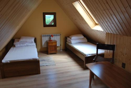 a attic room with two beds and a table at Gospodarstwo Agroturystyczne Wincentówka in Czarna