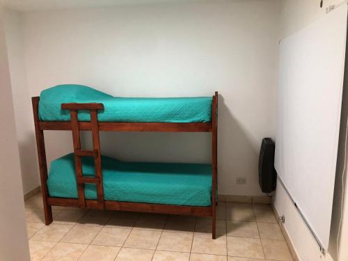 Litera en habitación con sábanas verdes en DPTOS 3 DE FEBRERO en San Pedro
