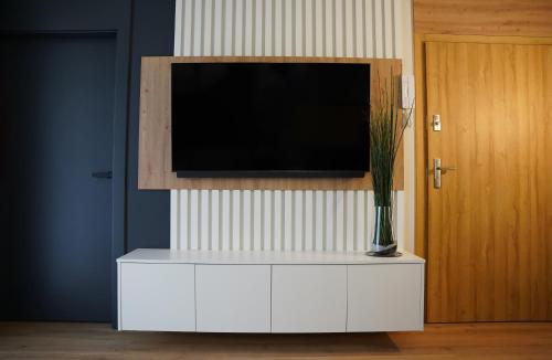 a white cabinet with a television on a wall at Apartamenty METRO TARGÓWEK 27 in Warsaw