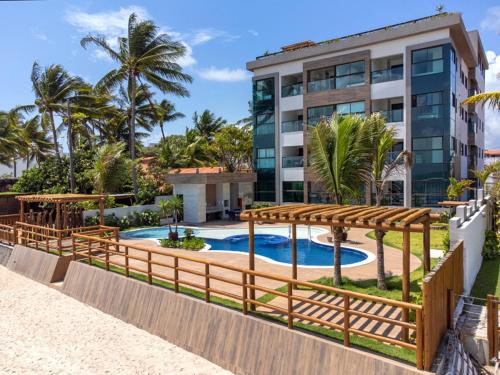 a resort with a swimming pool and a building at Apto Beira-mar vista piscinas naturais in Porto De Galinhas
