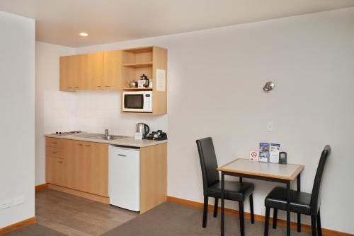 a kitchen with a table and chairs and a microwave at 306 Motel Apartments in Christchurch