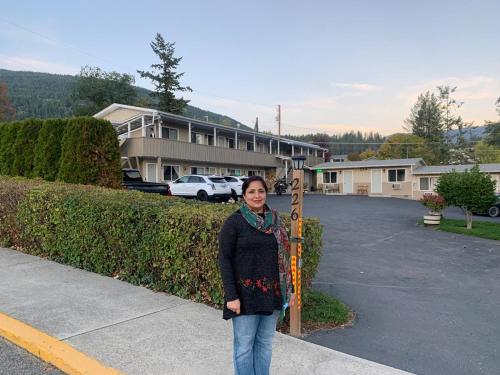 a woman standing on a sidewalk in a parking lot at City Centre Motel in Creston