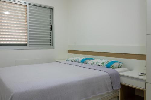 a white bedroom with a bed and a window at Apartamento Família em bairro nobre de Cuiabá! in Cuiabá