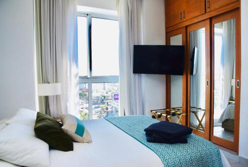 een slaapkamer met een bed, een televisie en een raam bij Apartamento S1404 Downtown Santo Domingo in Santo Domingo