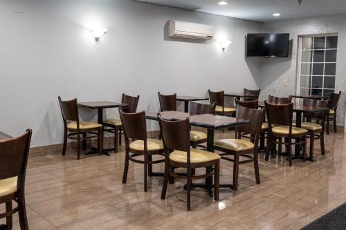 a dining room with tables and chairs and a flat screen tv at Hilltop Inn & Suites, near Foxwoods Casino in North Stonington