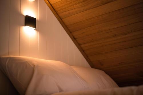 a bedroom with a white bed with a wooden ceiling at Tiny Escapes Cradle Valley in Moina