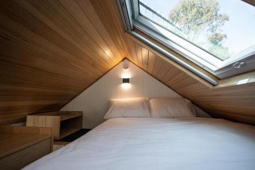 a bed in a small room with a window at Tiny Escapes Cradle Valley in Moina