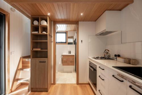 a kitchen with white counters and wooden ceilings at Tiny Escapes Cradle Valley in Moina