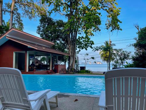 - une piscine avec 2 chaises et une maison dans l'établissement Holiday Resort - SHA Plus, à Ko Yao Noi