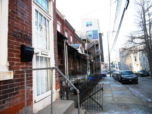 a brick building with a staircase next to a street at Oui on Ludlow - Entire House and Private Rooms in University City in Philadelphia