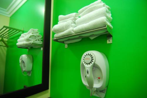 a bathroom with a green wall with towels and a mirror at Studio City Inn - Near Universal Studios Hollywood in Los Angeles