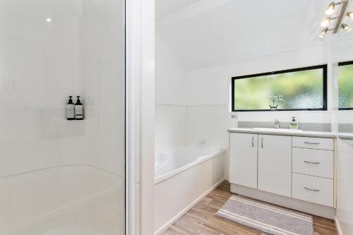 La salle de bains blanche est pourvue d'une baignoire et d'un lavabo. dans l'établissement Brind Lodge - Russell Holiday Home, à Russell