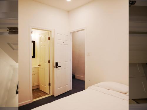 a white bedroom with a bed and a mirror at Oui on Ludlow - Entire House and Private Rooms in University City in Philadelphia