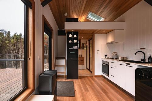 a kitchen with white cabinets and a large window at Tiny Escapes Cradle Valley in Moina