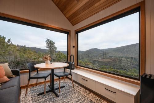 a room with large windows and a table and chairs at Tiny Escapes Cradle Valley in Moina