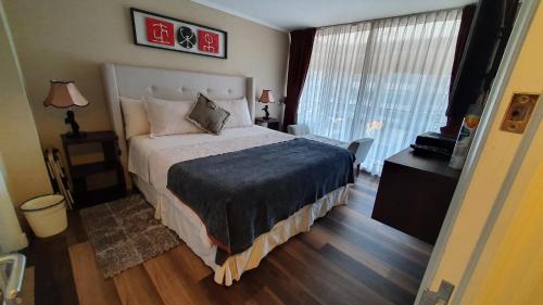 a bedroom with a large bed and a large window at Mojens Suites Santiago in Santiago