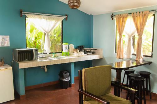 a kitchen with blue walls and a table with a microwave at Hotel y Bungalows El Jardín in San Felipe