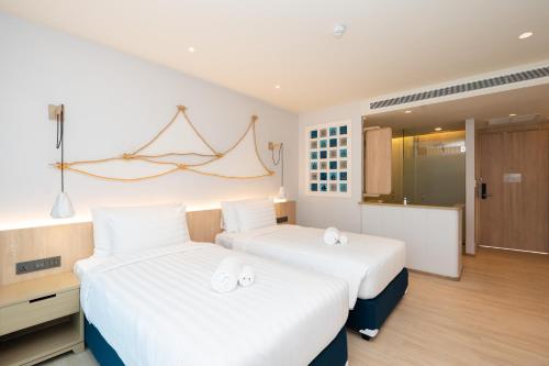 2 camas en una habitación de hotel con sábanas blancas en Panwaburi Beachfront Resort - SHA Extra Plus en Panwa Beach