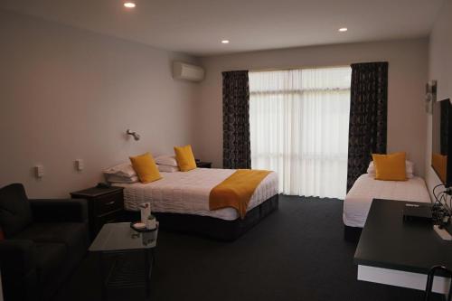 a hotel room with two beds and a couch and a window at Totara Lodge in Upper Hutt