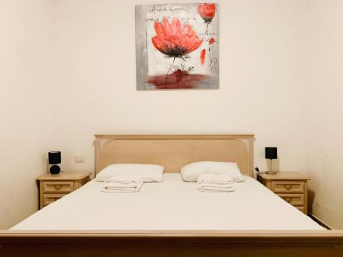 a bedroom with a bed with white sheets and a painting on the wall at Appartamento Bolzano Centro Talvera in Bolzano