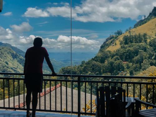 a man standing on a balcony looking out at the mountains at Paraiso Guest House in Ella