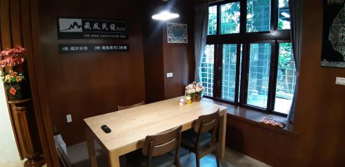 a wooden table and chairs in a room with windows at 藏風民宿THE WIND GUESTHOUSE 2022 in Tainan