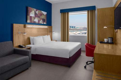 a hotel room with a bed and a chair and a window at Holiday Inn Express Dubai Airport, an IHG Hotel in Dubai