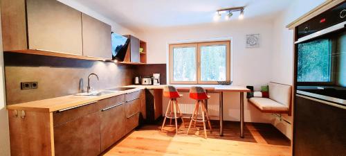 a kitchen with a sink and two red stools at Haus Tannenblick in Saalbach Hinterglemm