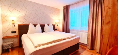 ザールバッハ・ヒンターグレムにあるHaus Tannenblickのベッドルーム1室(白いシーツ付きのベッド1台、窓付)