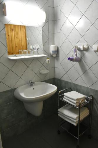 La salle de bains blanche est pourvue d'un lavabo et d'un miroir. dans l'établissement Lenti Thermal Panzió, à Lenti