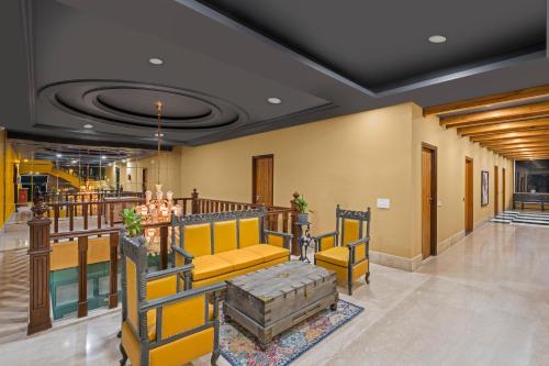 a lobby with yellow chairs and a table at The Atman Dharamshala by Leisure Hotels in Dharamshala